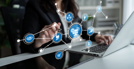 A confident businesswoman uses a laptop to analyze data trends with digital icons, showcasing technology and innovation in a professional office environment. Tessel