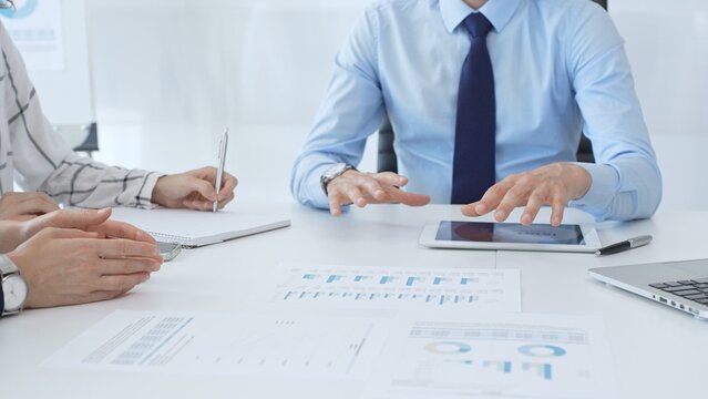 Business people reviewing financial metrics on digital screens, collaborating strategically while examining charts and graphs in office - Powered by Adobe