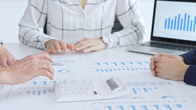 Business people or accouters analyzing financial data using charts, graphs, and reports during an office meeting, collaborating on strategy