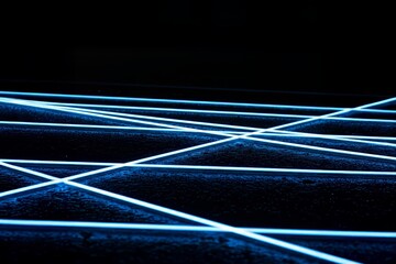 Stark abstract shot capturing intersecting electric blue neon lines on dark surface.