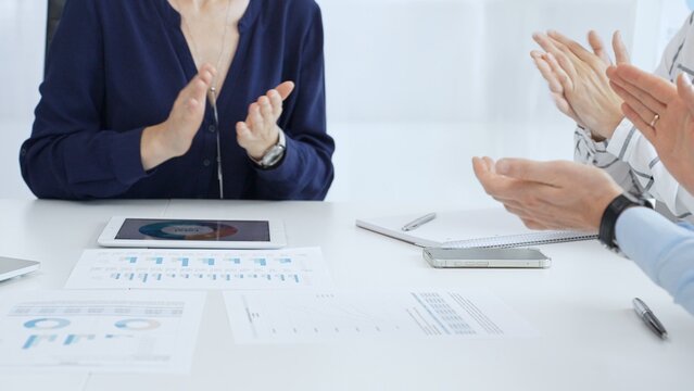 Business team applauding after successful presentation during a meeting in the office, celebrating achievement and good teamwork with positive attitude - Powered by Adobe