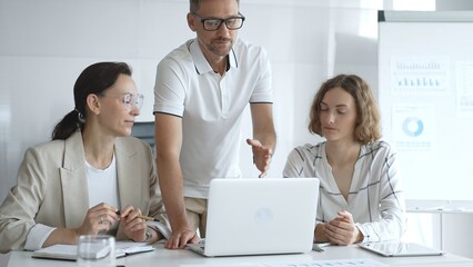 Business team collaborating and analyzing data on a laptop during a productive meeting in a modern office, fostering teamwork and strategic decision making