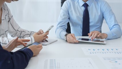 Business colleagues strategizing in modern workspace, reviewing financial analytics on digital devices, sharing insights through collaborative teamwork and data driven discussion