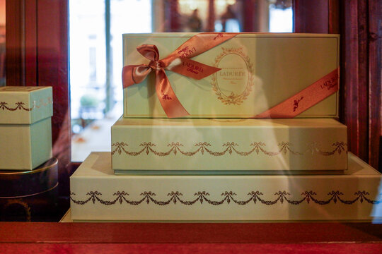 Paris, France - April 16, 2018: Elegant Laduree gift boxes displayed in a boutique window, showcasing luxurious packaging with ribbons and intricate designs, perfect for special occasions