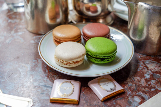 Paris, France - April 16, 2018: Colorful Laduree macarons on a decorative plate with chocolate squares, showcasing delightful pastries in a charming cafe setting, perfect for dessert lovers