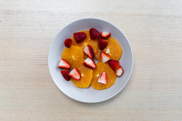 A plate of oranges and strawberries.