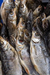 Close-up of dried fish arranged in a stack at a traditional food market.