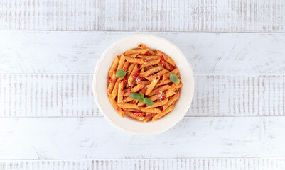Italian pasta arrabbiata with tomato sauce, chili pepper, parmesan on wooden background. Top view