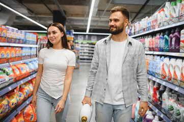Couple shopping household cleaning products in supermarket aisle