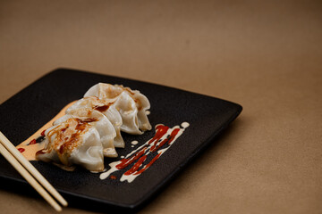 Pan-Fried Asian Dumplings with Sauce on Black Plate and offset left. 