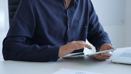 Fototapeta premium Businessman working with digital tablet and laptop computer at office desk, analyzing financial data and reports, developing business plan and strategy. Business people concept