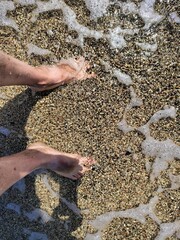 two legs standing on the sand on the seashore, half in the water