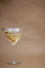 Classic Dry Martini with Green Olives in a Tall Cocktail Glass on Neutral Background
