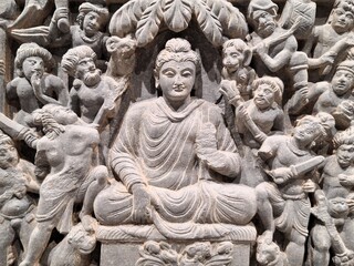 Close up of an ancient Buddhist temple wall relief, depicting the Buddha meditating under a tree, attacked by Mara