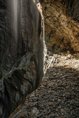 Rocky canyon wall with sunlight and falling water
