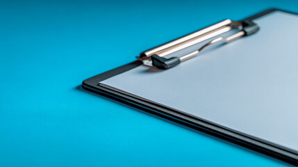 Close-up of a black clipboard holding blank white paper on a vibrant blue surface with soft focus in the background for office or school use concepts
