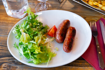 Appetizing fried sausages served with potatoes and salad on platter