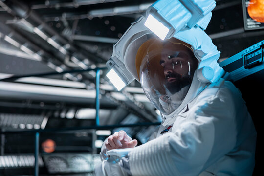 Cosmonaut flying in futuristic starship entering destination coordinates using suit device during cosmic journey. Astronaut in spacecraft mapping unknown worlds during long distance space travel - Powered by Adobe