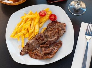 Juicy grilled beef filet steak served with side dish of crispy roasted potatoes and fresh tomatoes..