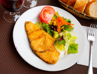 Arbitrary pieces of Peking cabbage, grated carrots, corn and slice of tomato successfully complement juicy stuffed fillet of white fish. Andalusian recipe for fish cooked by chef of restaurant