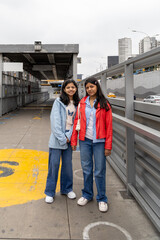 Two teenagers in blue and red jackets pose for a picture