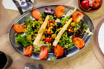 Traditional Spanish mixed salad, made from corn, tomato, lettuce, olives, asparagus, bell peppers on table