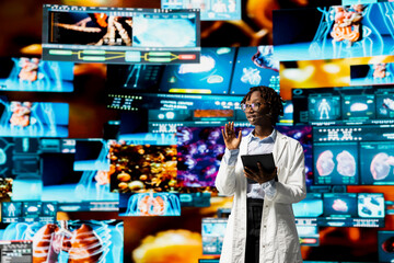 Female researcher doing key note presentation using holographic medical data charts. African american biomedical expert presents human organ diagnostics scans diagrams to audience at event