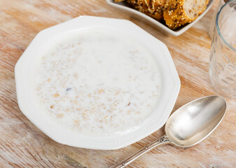 There is portion of freshly prepared oatmeal porridge in plate. Traditional dietary European breakfast.