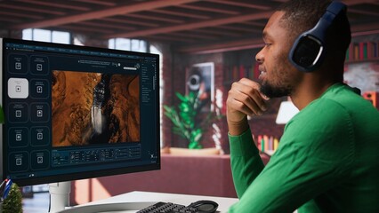 Computer screen displays digital visuals generated through AI. Young person uses software combining data and machine learning, text prompts to design graphics at home office. Camera B.