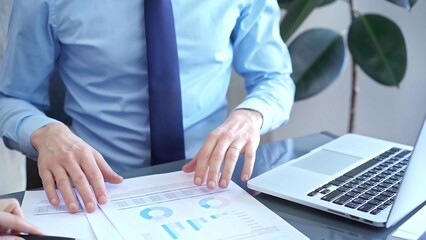 Obraz premium Businessman and woman analyzing data at glass desk beside a laptop in modern office, close up view. Business concept
