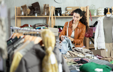 Armenian woman stands near the counter in a clothing store and chooses fleece jeans for cold weather. Buying woolen pants, warm trousers and jeans