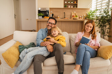 Family relaxing on sofa watching television and reading book
