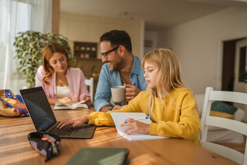 Little girl doing homework and learning online with parents