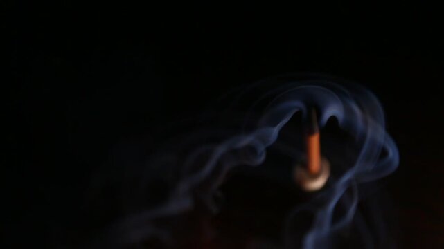 Smoldering aroma incense on dark background with natural atmosphere concept smoke. Magic calm waves from herb incense. Therapy and spa fumigation concept