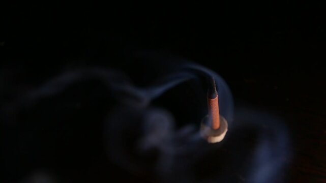 Smoldering aroma incense on dark background with natural atmosphere concept smoke. Magic calm waves from herb incense. Therapy and spa fumigation concept