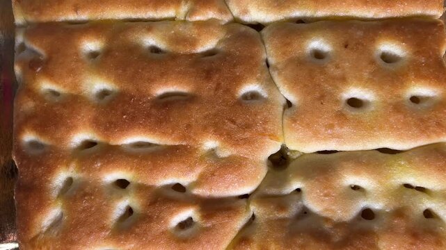 Focaccia bread ligurian tipical of Genova - flatbread of sourdough and olive oil tracking shot in close up