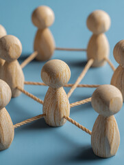 Obraz premium Wooden figures connected with ropes forming a network symbolizing teamwork collaboration and interconnected communication on a blue surface background