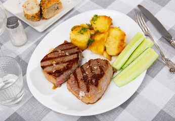 Juicy beef steak with potatoes; served with cucumber and herbs