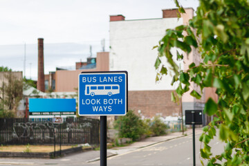 Bus lanes look both ways sign with city street and chimney