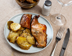 Delicious fried rabbit cuts served with baked potatoes on plate for dinner. European cuisine..