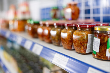 Glass jars with mustard on the shelves of a grocery supermarket