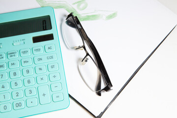 Calculator and eyeglasses on the white background, business concept
