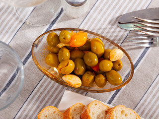 Green pitted olives in bowl with pickled garlic and onions