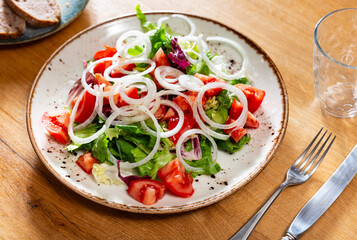 Appetizing salad of fresh vegetables with tomato and onion served on platter