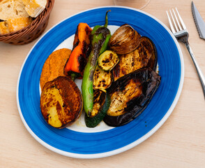 Appetizing grilled vegetables with potatoes and romesco sauce served on plate
