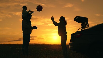 Travelling by car. Family picnic nature. Dad with child, daughter, mother, children play with ball against sunset next to car. Happy family travels by car. Parents, children stopped at campsite by car