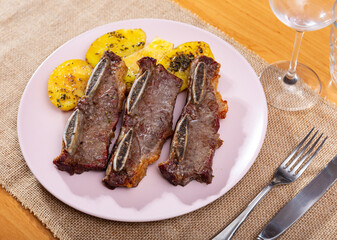Hearty lunch dish from chef - churasco with potatoes. Fried veal ribs on bone, garnished with potatoes