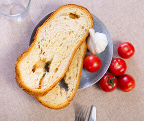 Ingredients for traditional Spanish appetizer Pa amb tomaquet, crispy toasted bread, fresh tomatoes, garlic on plates and decanter with olive oil, served on table