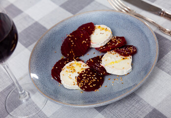Delicious sliced goat cheese with beet slices and honey served on platter