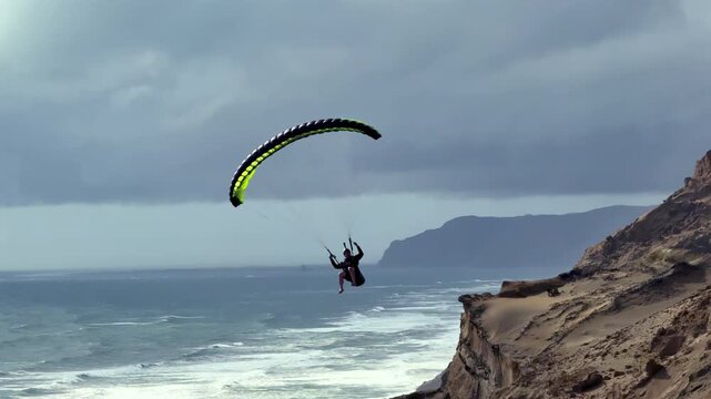 Extreme paragliding pilot soaring in the New Zealand beach. Adventure concept.